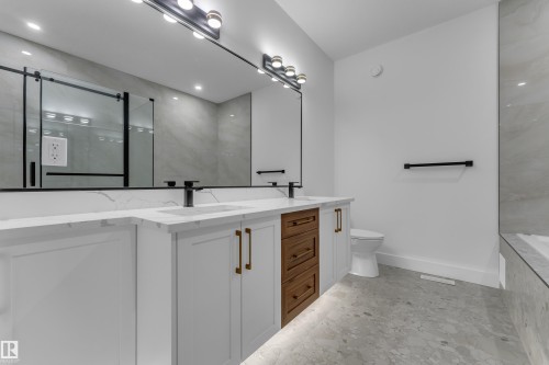 Dual vanity with white cabinetry and wood-finish drawers, matte black fixtures, and white countertops - 3604 44 Avenue, Beaumont, AB 