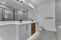 Dual vanity with white cabinetry and wood-finish drawers, matte black fixtures, and white countertops - 