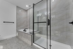 Walk-in shower with clear glass enclosure and black frame, featuring a built-in tub with matte black fixtures - 
