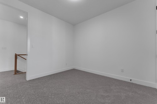 Recessed ceiling lighting, light gray patterned carpeting, white walls, and a wood handrail - 3604 44 Avenue, Beaumont, AB 
