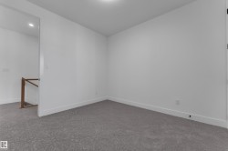 Recessed ceiling lighting, light gray patterned carpeting, white walls, and a wood handrail - 