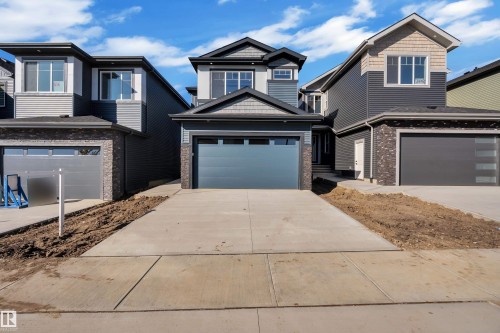 Contemporary exterior design with multi-pane windows, dark-toned siding, stone-finish accents, and an integrated garage - 3604 44 Avenue, Beaumont, AB 