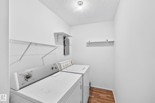 Dedicated laundry area featuring wood-finish flooring and integrated wire shelving - #212 11218 80 St Nw, Edmonton, AB 