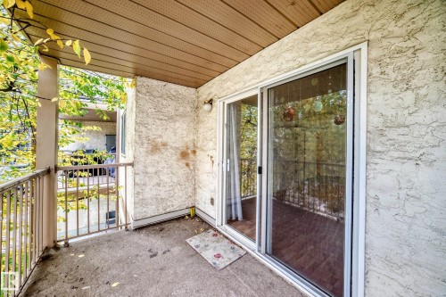 Balcony with a textured exterior wall, overhead covering, and metal railings - #212 11218 80 St Nw, Edmonton, AB 