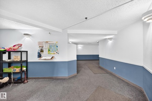 Wall-mounted sconce lighting, two-tone wall treatment, and textured ceiling finish - #212 11218 80 St Nw, Edmonton, AB 