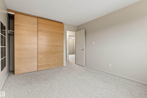 Neutral-toned walls with custom light-finish wood sliding closet doors and wall-to-wall carpeting - 55 Royal Road Nw, Edmonton, AB 