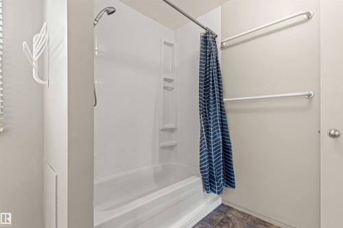 Acrylic shower-tub combination featuring built-in shelving, an adjustable showerhead, and dual wall-mounted safety rails - 55 Royal Road Nw, Edmonton, AB 