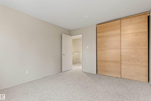 Neutral-toned interior space featuring wall-to-wall carpeting and floor-to-ceiling built-in wardrobe with natural wood-finish sliding doors - 55 Royal Road Nw, Edmonton, AB 