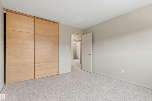 Neutral-toned interior space featuring light-colored wall-to-wall carpeting and floor-to-ceiling sliding closet doors with a wood finish - 55 Royal Road Nw, Edmonton, AB 