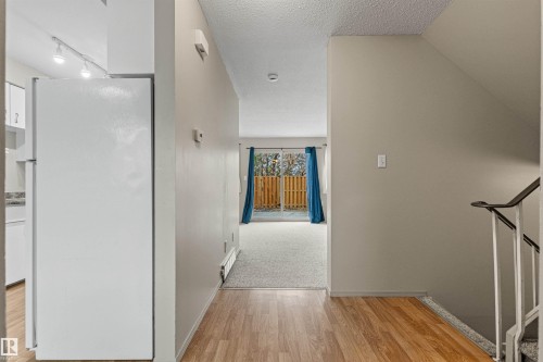 Interior space featuring wood-finish flooring, staircase with metal railing, sliding glass doors, and track lighting - 55 Royal Road Nw, Edmonton, AB 