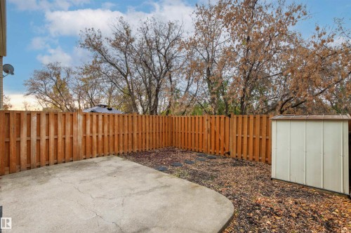 Fenced backyard featuring a concrete patio, wood privacy fencing, a metal storage structure, and stone stepping path - 55 Royal Road Nw, Edmonton, AB 
