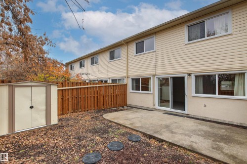 Exterior featuring horizontal siding, concrete patio, sliding glass door, wooden privacy fencing, and metal storage shed - 55 Royal Road Nw, Edmonton, AB 