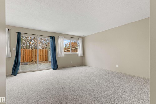 Neutral wall tones, carpeted flooring, sliding glass door, and exterior window - 55 Royal Road Nw, Edmonton, AB 
