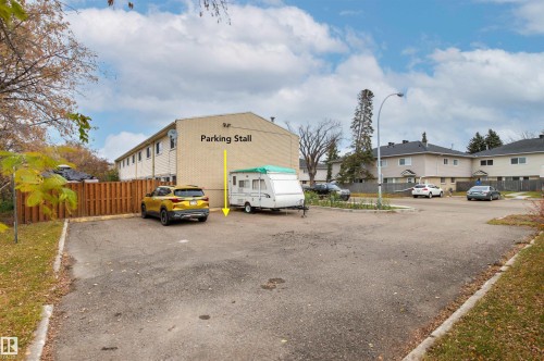 Asphalt parking lot featuring designated stall space and wood fencing - 55 Royal Road Nw, Edmonton, AB 