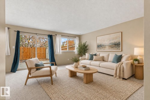 Neutral-toned living space featuring wall-to-wall carpeting, sliding glass doors, and a horizontal window. - 55 Royal Road Nw, Edmonton, AB 