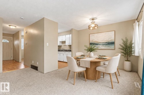 Neutral interior featuring wall-to-wall carpeting, wood-finish flooring, white cabinetry, and a decorative pendant light fixture - 55 Royal Road Nw, Edmonton, AB 
