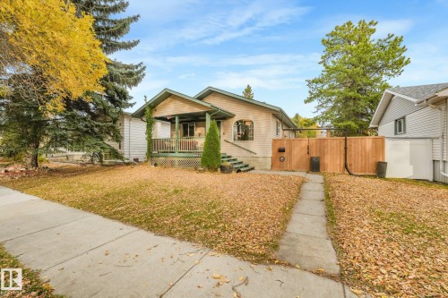 Single-story residence featuring a covered front porch, horizontal lap siding, an arched window, and a wood privacy fence - 9617 151 Street Nw, Edmonton, AB 