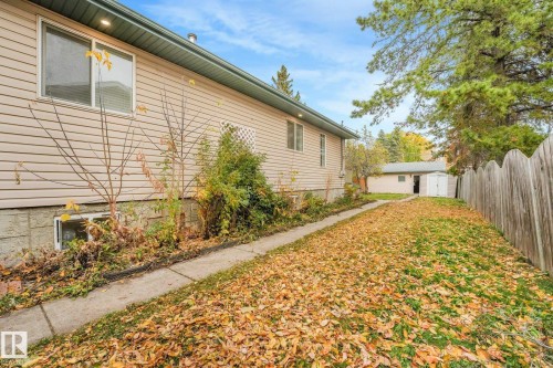 Exterior featuring horizontal siding, concrete foundation, paved walkway, wooden privacy fencing, and detached structure - 9617 151 Street Nw, Edmonton, AB 