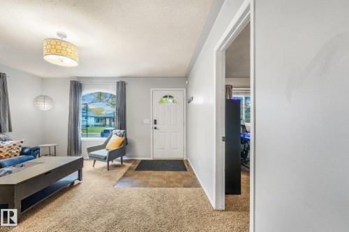 Entryway featuring a stone-tile floor, an exterior door with a decorative glass insert, an arched window, and dual drum-style ceiling light fixtures - 9617 151 Street Nw, Edmonton, AB 