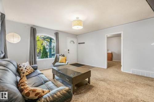 Arched window with exterior views, patterned drum-style ceiling light fixture, and neutral wall color palette - 9617 151 Street Nw, Edmonton, AB 