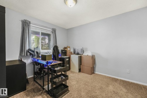 Neutral-toned interior space featuring carpeted flooring, a sliding window, and a central ceiling-mounted light fixture - 9617 151 Street Nw, Edmonton, AB 
