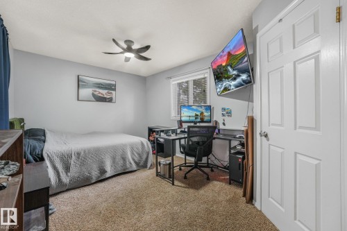 Neutral-toned interior featuring wall-to-wall carpeting, a ceiling-mounted light fixture with fan, a multi-pane window with blinds, and a six-panel interior door - 9617 151 Street Nw, Edmonton, AB 