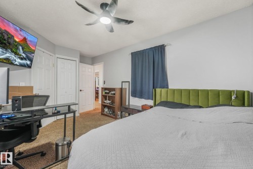 Interior space featuring a ceiling fan with integrated lighting, textured carpeting, and multiple interior paneled doors - 9617 151 Street Nw, Edmonton, AB 
