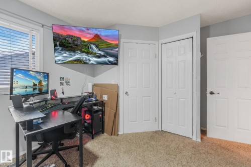 Neutral-toned wall paint, wall-mounted television bracket, multi-panel doors, closet with folding doors, and carpeting - 9617 151 Street Nw, Edmonton, AB 