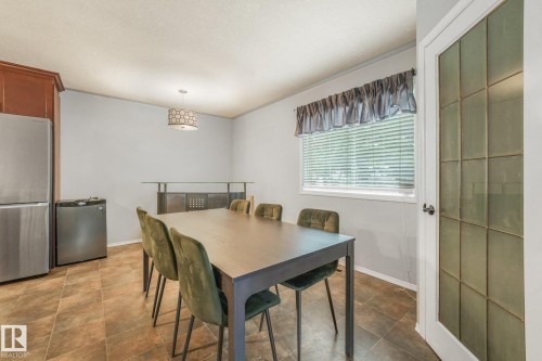 Ceramic tile flooring, built-in wooden cabinetry, stainless steel refrigerator, drum-style pendant lighting, and a multi-pane glass door with white casing - 9617 151 Street Nw, Edmonton, AB 