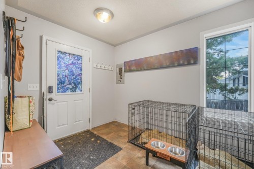 Entryway featuring tile flooring, a door with a decorative glass panel, a built-in wall-mounted coat rack, and a multi-pane window - 9617 151 Street Nw, Edmonton, AB 