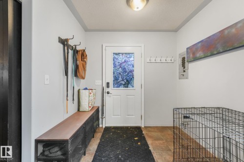 Entryway featuring an exterior door with a decorative glass insert, neutral wall paint, and ceramic tile flooring - 9617 151 Street Nw, Edmonton, AB 