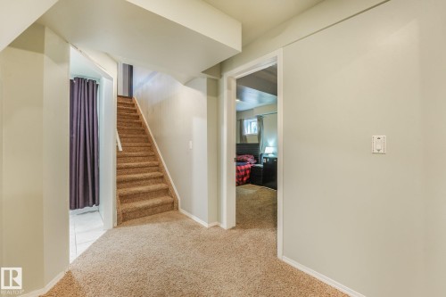 Interior hallway featuring neutral wall paint, carpeted flooring, and a staircase with carpeted treads - 9617 151 Street Nw, Edmonton, AB 
