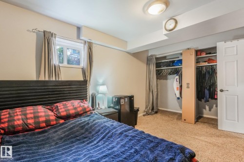 Room interior featuring neutral wall paint, carpeted flooring, a closet with built-in shelving, and a double-panel door - 9617 151 Street Nw, Edmonton, AB 