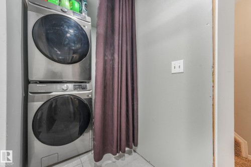 Stacked laundry alcove featuring stainless steel appliances and tile flooring - 9617 151 Street Nw, Edmonton, AB 