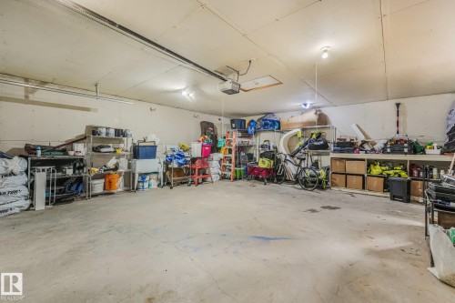 Spacious multi-car garage featuring a concrete floor, high ceilings, built-in shelving, and an automatic door opener - 9617 151 Street Nw, Edmonton, AB 