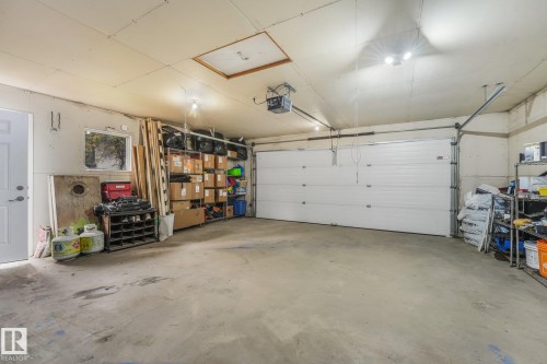 Multi-car garage featuring a wide sectional overhead door, concrete flooring, attic access panel, and a dedicated side-entry door - 9617 151 Street Nw, Edmonton, AB 