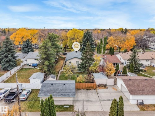 Residential lot featuring a detached garage, concrete driveway, wood privacy fencing, and mature evergreen trees - 9617 151 Street Nw, Edmonton, AB 