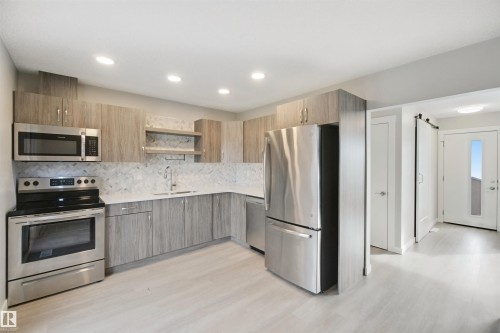 Modern kitchen featuring stainless steel appliances, light wood-finish cabinetry, a white countertop, and recessed lighting - 13212 73 Street Nw, Edmonton, AB 