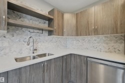 Wood-finish cabinetry and open shelving complement the white countertop and herringbone tile backsplash - 