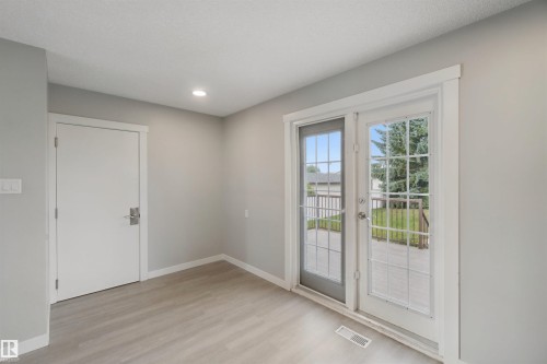Wood-finish flooring, recessed ceiling lighting, light gray wall color, white trim, and a glass-paneled double door leading to a patio - 13212 73 Street Nw, Edmonton, AB 