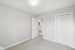 Soft grey carpeting, neutral wall color, contemporary flush-mount ceiling light, white bi-fold closet doors, and white interior door with polished chrome hardware - 