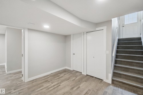 Wood-finish flooring, recessed ceiling lighting, two bi-fold closet doors, white interior doors, and a carpeted staircase - 13212 73 Street Nw, Edmonton, AB 