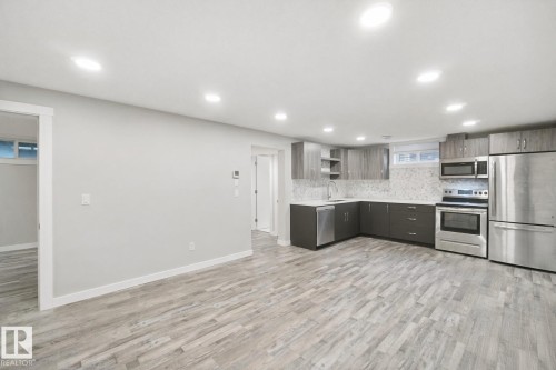 Contemporary kitchen featuring stainless steel appliances, grey cabinetry, light countertops, a patterned backsplash, and recessed lighting - 13212 73 Street Nw, Edmonton, AB 
