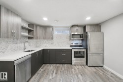 Modern kitchen featuring stainless steel appliances, wood-finish flooring, two-tone cabinetry, herringbone tile backsplash, and recessed lighting - 