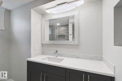 Vanity featuring a white countertop with an integrated sink, polished chrome faucet, and dark wood-finish cabinetry - 