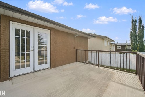 Outdoor deck with white French doors, brown metal railings, and a stucco exterior finish - 13212 73 Street Nw, Edmonton, AB 