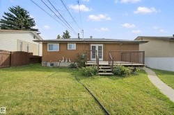 Expansive backyard featuring a manicured lawn, established landscaping, and a privacy fence - 