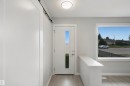 Contemporary entryway featuring a front door with vertical window insert, a side-mounted barn door track, wood-finish flooring, and a large picture window - 13212 73 Street Nw, Edmonton, AB 