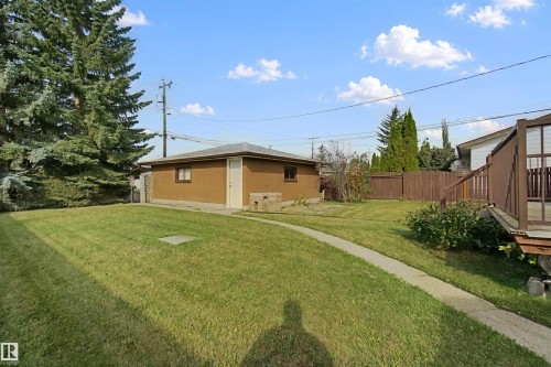 Expansive grassy yard featuring a concrete pathway, detached auxiliary building, wood privacy fencing, and mature trees - 13212 73 Street Nw, Edmonton, AB 