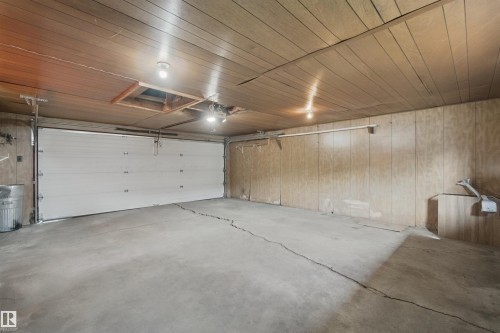 Attached garage featuring a concrete floor, wood-finish paneling, and overhead lighting - 13212 73 Street Nw, Edmonton, AB 